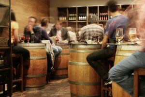 Image of multiple people at a winery sitting and drinking alcohol. How long does alcohol stay in your system. When does alcohol get out of your system